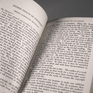 Op de afbeelding: Een close-up van een open boek met de titel "Second Speech on Copyright" van Thomas Babington Macaulay. De tekst bespreekt de duur van auteursrechten en de argumenten voor en tegen het verlengen ervan.