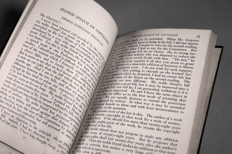 Op de afbeelding: Een close-up van een open boek met de titel "Second Speech on Copyright" van Thomas Babington Macaulay. De tekst bespreekt de duur van auteursrechten en de argumenten voor en tegen het verlengen ervan.