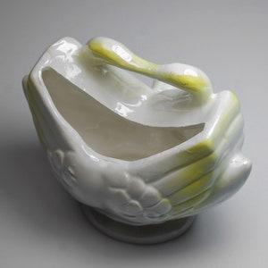 May include: White ceramic planter shaped like two birds with yellow accents. The planter is empty and ready for a plant.