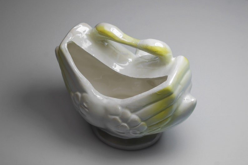 May include: White ceramic planter shaped like two birds with yellow accents. The planter is empty and ready for a plant.