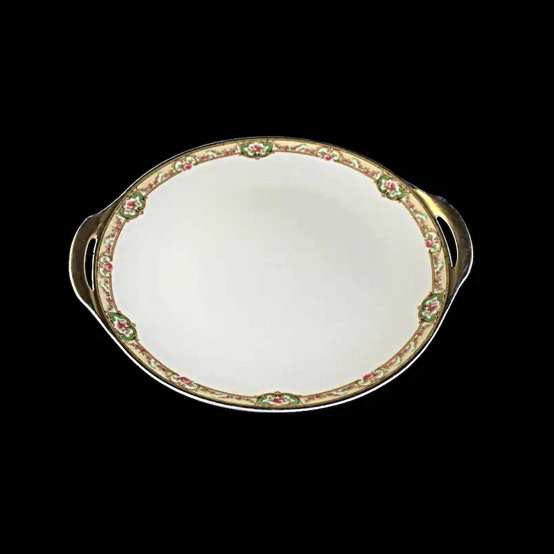 May include: A white oval serving platter with gold trim and a floral design. The platter has two handles.