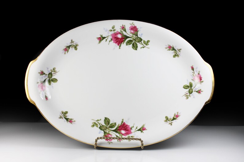 Puede incluir: Plato de servir ovalado blanco con borde dorado y dise&ntilde;o floral con rosas rosas y hojas verdes.