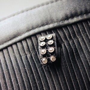 May include: A black fabric with a silver and black embellishment featuring a row of clear rhinestones.