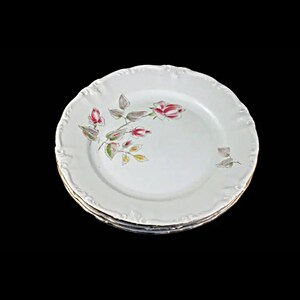May include: Set of three white porcelain dinner plates with a delicate floral design featuring pink roses and green leaves. The plates have a gold rim.