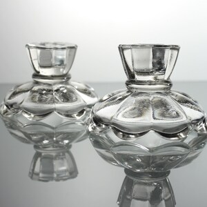 Puede incluir: Dos candelabros de vidrio transparente con base festoneada y parte superior acanalada.