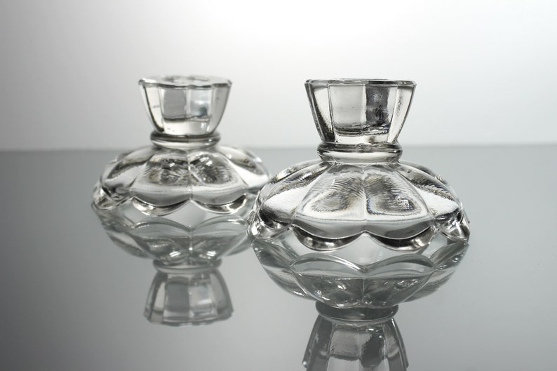 Puede incluir: Dos candelabros de vidrio transparente con base festoneada y parte superior acanalada.