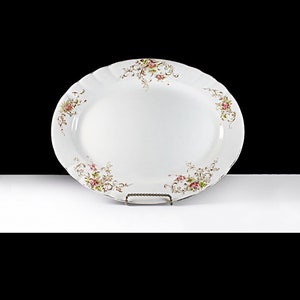 Puede incluir: Plato de servir ovalado blanco con un delicado diseño floral en tonos rosa y verde. El plato tiene un borde festoneado y es perfecto para servir una variedad de platos.