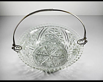 May include: A clear glass bowl with a cut glass design and a silver metal handle. The bowl is ideal for serving snacks or desserts.