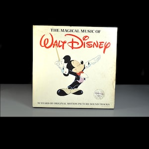 Könnte beinhalten: Ein Vintage-Albumcover für "The Magical Music of Walt Disney". Das Cover zeigt Micky Maus beim Dirigieren eines Orchesters. Das Album feiert 50 Jahre Original-Filmmusik. Der Text ist in Rot und Schwarz.