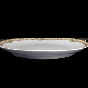 May include: A white oval serving platter with a floral design in shades of pink, green, and gold. The platter has two handles on the sides.