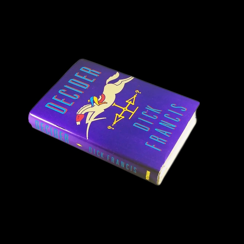 May include: A purple paperback book titled "Decider" by Dick Francis. The cover features a colorful illustration of a horse and rider.