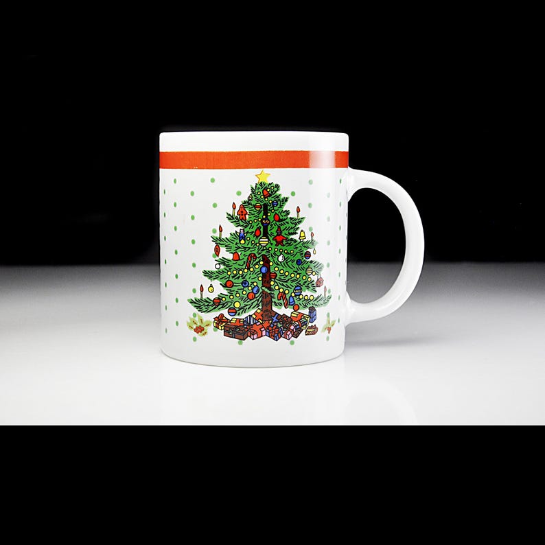 May include: White ceramic mug with a red stripe and green polka dots. The mug features a colourful illustration of a Christmas tree decorated with baubles and presents.