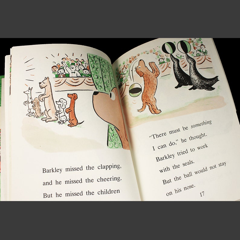May include: A brown dog with a black nose watches a group of seals balancing balls on their noses. The seals are black with white stripes. The dog is looking at the seals with a curious expression. The text "There must be something I can do." is written in the bottom right corner of the page.