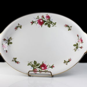 Puede incluir: Plato de servir ovalado blanco con borde dorado y dise&ntilde;o floral con rosas rosas y hojas verdes.