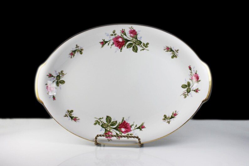 Puede incluir: Plato de servir ovalado blanco con borde dorado y dise&ntilde;o floral con rosas rosas y hojas verdes.
