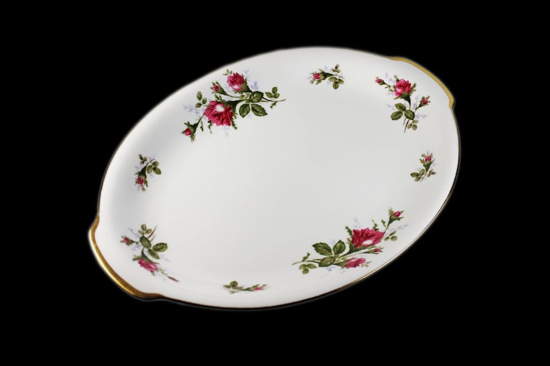 Puede incluir: Plato de servir ovalado blanco con borde dorado y dise&ntilde;o floral con rosas rosas y hojas verdes.