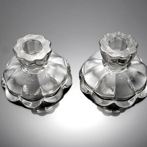 Puede incluir: Dos candelabros de vidrio transparente con borde festoneado y dise&ntilde;o acanalado. Los candelabros est&aacute;n vac&iacute;os y listos para usar.
