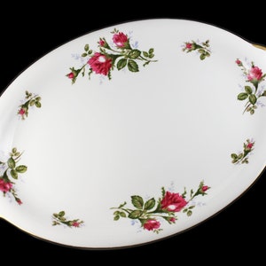 Puede incluir: Plato de servir ovalado blanco con borde dorado y dise&ntilde;o floral con rosas rosas y hojas verdes.