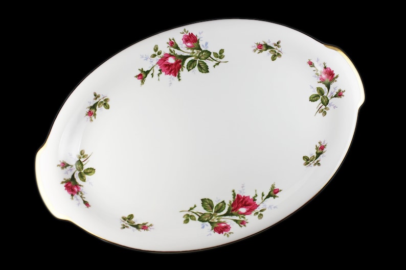 Puede incluir: Plato de servir ovalado blanco con borde dorado y dise&ntilde;o floral con rosas rosas y hojas verdes.