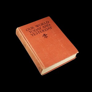 May include: A red hardback book with the title "Our World Today and Yesterday" printed in black lettering. The book has a decorative design on the front cover.
