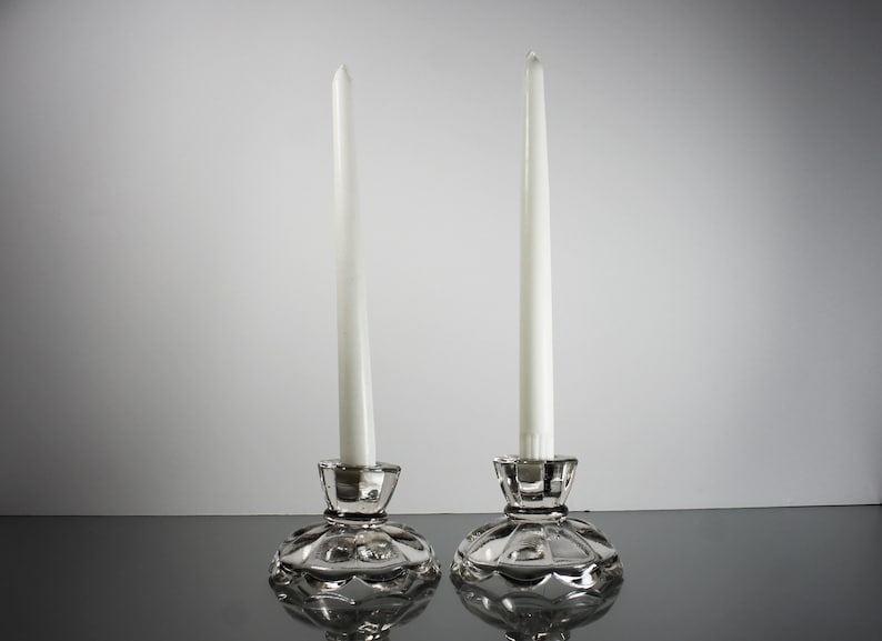 Puede incluir: Dos candelabros de cristal transparente con velas blancas. Los candelabros tienen un dise&ntilde;o festoneado.
