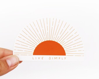 May include: A white sticker with an orange sun and gold rays. The text "LIVE SIMPLY" is below the sun.