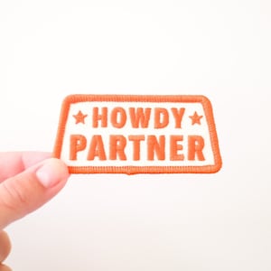 May include: Orange embroidered patch with white text that reads "Howdy Partner" and two white stars.