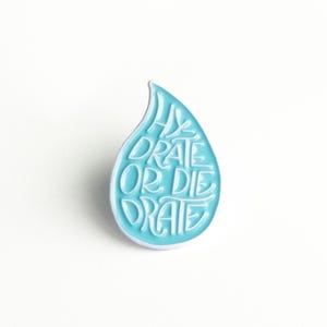 May include: A blue enamel pin shaped like a water drop with the text "Hydrate or Die-drate" in white.
