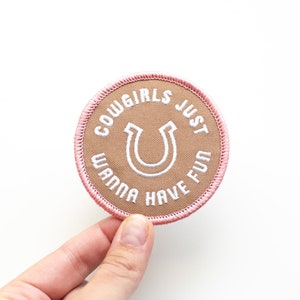 May include: A brown and pink embroidered patch with a white horseshoe and the text "Cowgirls Just Wanna Have Fun".