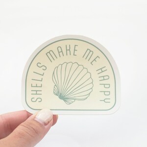 May include: A beige and green sticker with a seashell and the text "Shells make me happy".