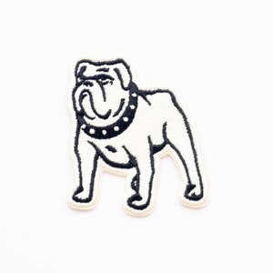 May include: Black and white embroidered patch of a bulldog wearing a studded collar.
