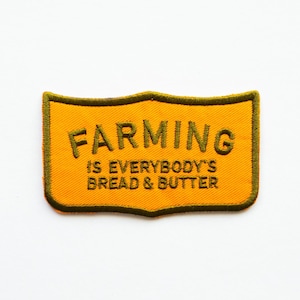May include: A yellow and green embroidered patch with the text "Farming is everybody's bread & butter."