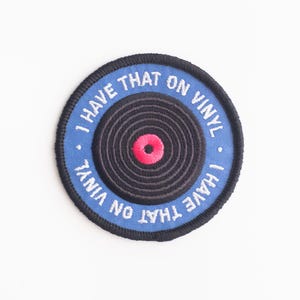 May include: A blue and white embroidered patch with a black vinyl record design. The text on the patch reads "I have that on vinyl - I have that on vinyl".