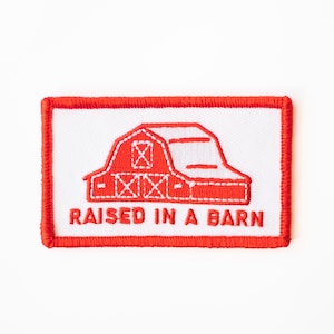 May include: Red embroidered patch with a white outline of a barn and the text "RAISED IN A BARN".