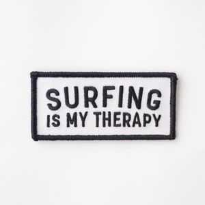 May include: White embroidered patch with black stitching. The patch reads "Surfing is my therapy."