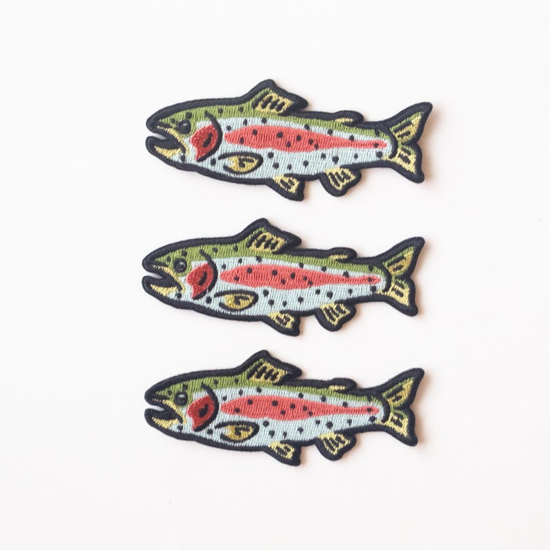 May include: Three embroidered iron-on patches of rainbow trout fish. The fish are green, yellow, red, and blue with black outlines.