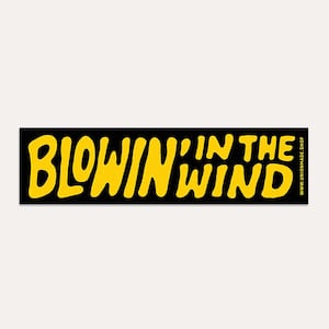 May include: A black rectangular sticker with the words "BLOWIN' IN THE WIND" in yellow, stylized, bubble letters. The website address www.unionmade.shop is in white text on the right side.