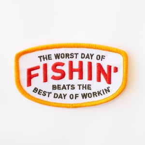 May include: White embroidered patch with orange stitching. The patch reads "The worst day of fishin' beats the best day of workin'"