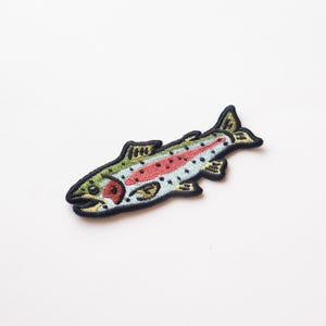 May include: An embroidered iron-on patch of a rainbow trout fish with black outlines, green, yellow, red, and blue details.