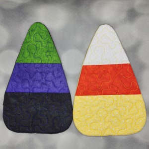 May include: Two felt candy corn ornaments. One is green, purple, and black. The other is white, orange, and yellow.