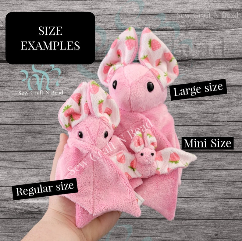 Puede incluir: Tres murci&eacute;lagos de peluche rosa de diferentes tama&ntilde;os con alas de tela de estampado de fresa. Los murci&eacute;lagos est&aacute;n etiquetados como "Tama&ntilde;o grande", "Tama&ntilde;o regular" y "Tama&ntilde;o mini".