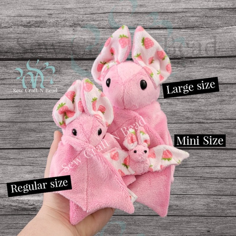 Puede incluir: Tres murci&eacute;lagos de peluche rosa con tela estampada de fresa. Los murci&eacute;lagos son de diferentes tama&ntilde;os: mini, regular y grande. El texto "Sew Craft N Bead" es visible en los murci&eacute;lagos.