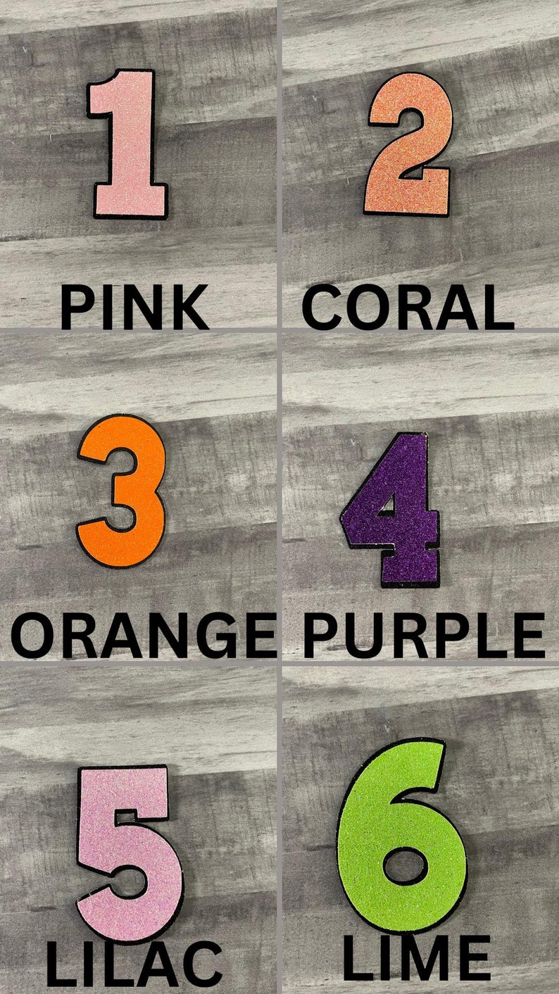 May include: Six colorful numbers, each with a black outline, are displayed against a gray background. The numbers are pink, coral, orange, purple, lilac, and lime green. Each number has a corresponding color name written below it.