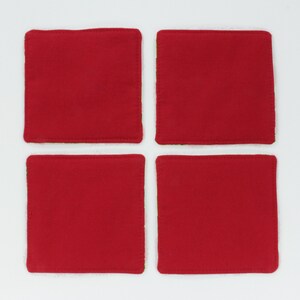 May include: Set of four red and green square coasters. The coasters are made of fabric and have a stitched edge.