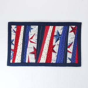 May include: A blue, red, and white quilted table runner with a patriotic star design.