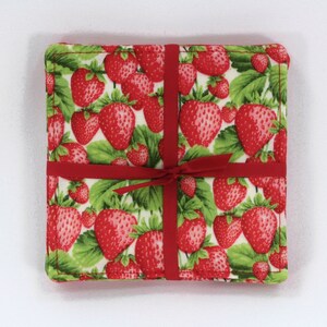 May include: Set of four red and green fabric coasters with a strawberry print. The coasters are tied together with a red ribbon.