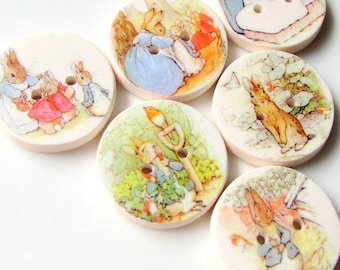 May include: Set of eight round ceramic buttons featuring illustrations of Peter Rabbit and other characters from the Beatrix Potter stories. The buttons are white with colorful illustrations.