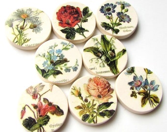 May include: Eight round, white ceramic buttons with floral designs. Each button features a different flower, including a rose, daisy, forget-me-not, and lily of the valley. The buttons have two holes for sewing.