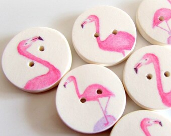 Op de afbeelding: Zes witte ronde knopen met roze flamingo-illustraties. Elke knop heeft twee gaten om te naaien.