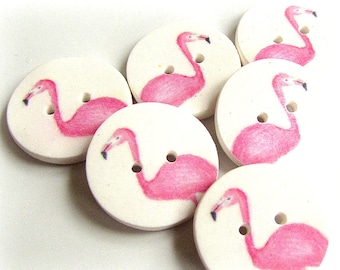 May include: Six pink flamingo buttons with white backgrounds. The buttons are round and have a diameter of approximately 1 inch.